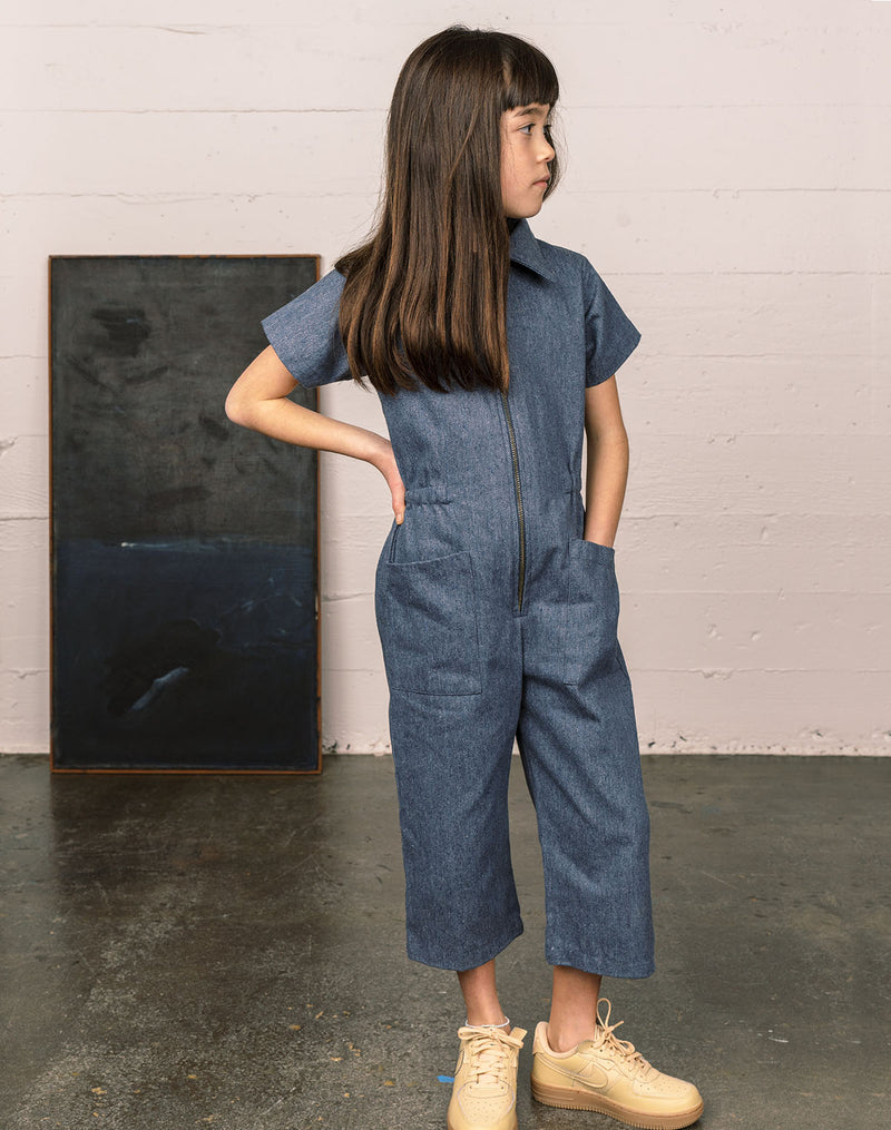 Girl wearing a denim utility suit made with upcycled denim materials and a metal YKK zipper
