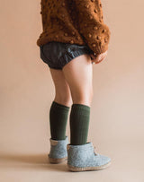 Baby wearing brown popcorn sweater,  bloomers, knee socks and grey Glerups wool baby boots